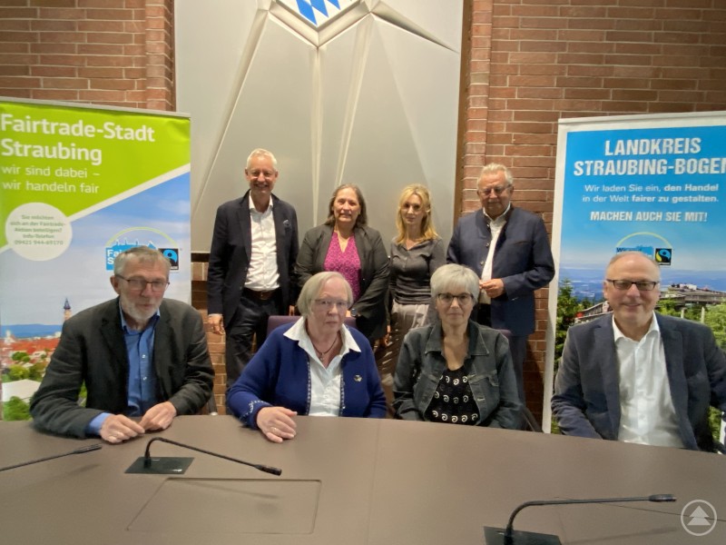 Auftaktveranstaltung zur Fairen Woche 2025 im Landratsamt: Vertreterinnen und Vertreter der Steuerungsgruppen von Stadt und Landkreis Straubing-Bogen gemeinsam mit Pate Stephan Stadler. Acht Personen – vier vorne sitzend, vier hinten stehend – posieren im Sitzungssaal vor Bannern zu Fairtrade-Stadt Straubing und Landkreis Straubing-Bogen.