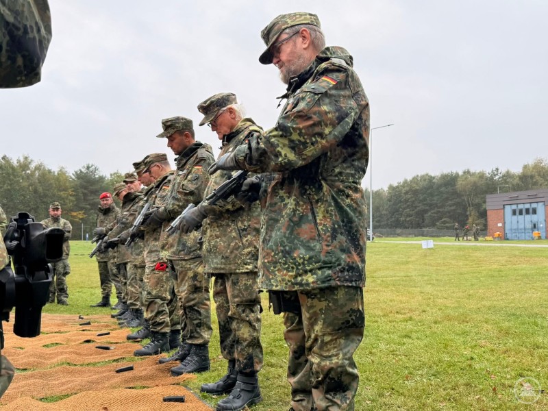 Reservisten in Tarnuniform beim praktischen Schießtraining mit Gewehr auf dem Übungsplatz.