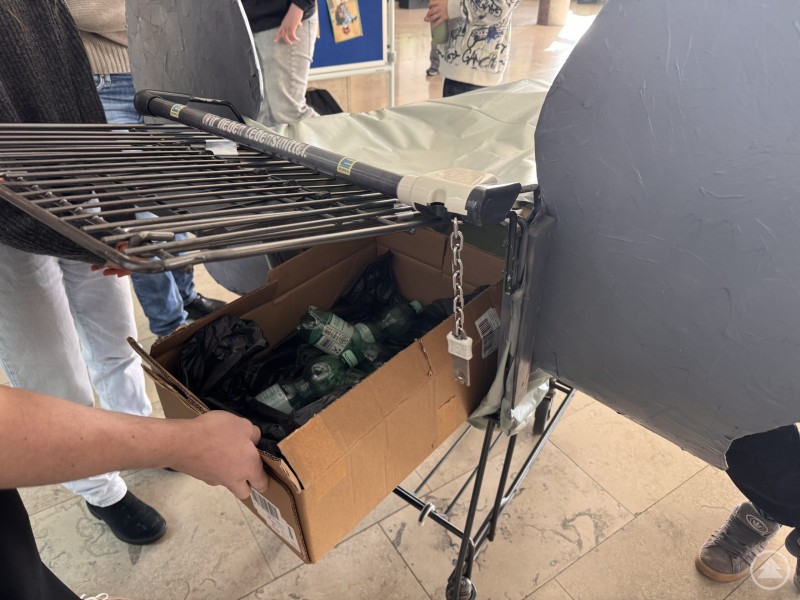 Ein Blick ins Innere des (P)FANTOMAT zeigt, wie die gesammelten Pfandflaschen im umgebauten Wagen landen Nahaufnahme des Innenraums des (P)FANTOMAT. In einer Kiste im umgebauten Wagen liegen bereits gesammelte Pfandflaschen.