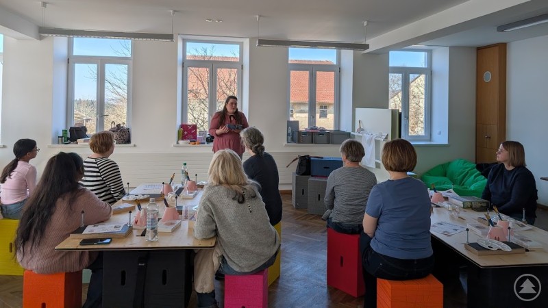 Die Einleitung eines Workshops in der Macherei in Thurmansbang Die Seminarteilnehmer lauschen Carmen Knorrs Einleitung, sitzen aber schon an ihren Tischen mit ihren Büchern und vorbereiteten Material