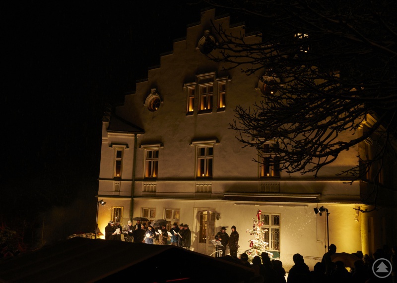 Ein Männerchor singt vor dem festlich beleuchteten Schloss