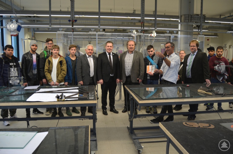 Vielfältige Ausbildungsberufe der Glasfachschule Zwiesel präsentierten Erwin Donnerbauer (4. von rechts) und Michael Horina (2. von rechts) den faszinierten Schülern, Landrat Adam (Mitte), Geschäftsführer Herbert Unnasch (6. von links) und Regionalmanager Stephan Lang (1. von rechts).