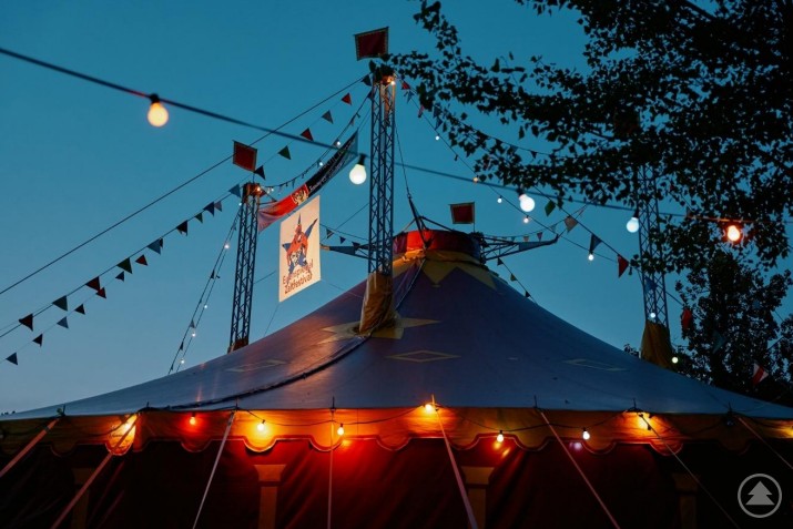 Vom 9. bis 27. Juli 2025 bietet das Eulenspiegel Zeltfestival in Passau ein vielseitiges Programm aus Kabarett, Konzerten und Comedy. Ein sommerlich beleuchtetes Zelt im Außenbereich bei Dämmerung, im Hintergrund Bäume und Lichter.