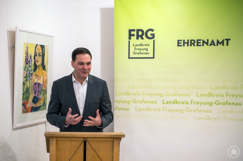 Landrat Sebastian Gruber spricht am Rednerpult vor dem Hintergrund des Logos Landkreis Freyung-Grafenau Ehrenamt.
