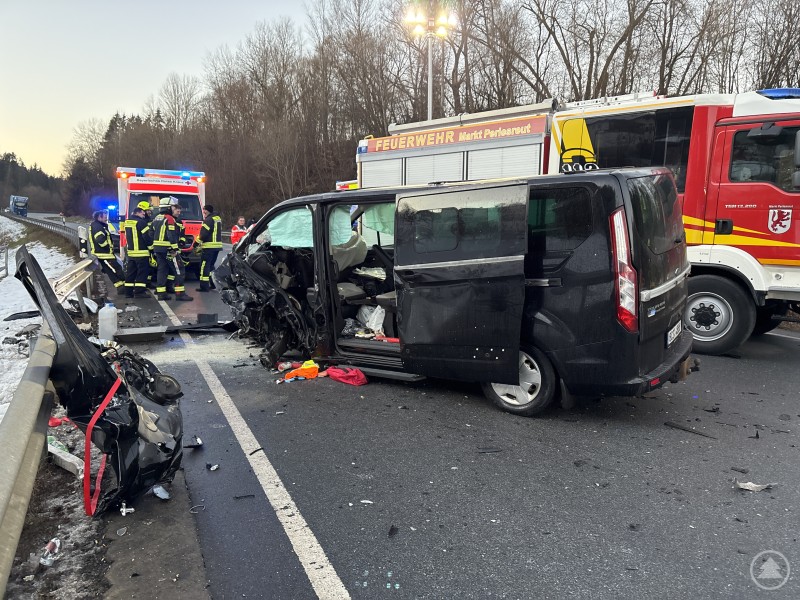 Schwer besch&auml;digter Kleintransporter steht nach einem Unfall auf einer Stra&szlig;e, Einsatzkr&auml;fte von Feuerwehr und Rettungsdienst sichern die Unfallstelle.