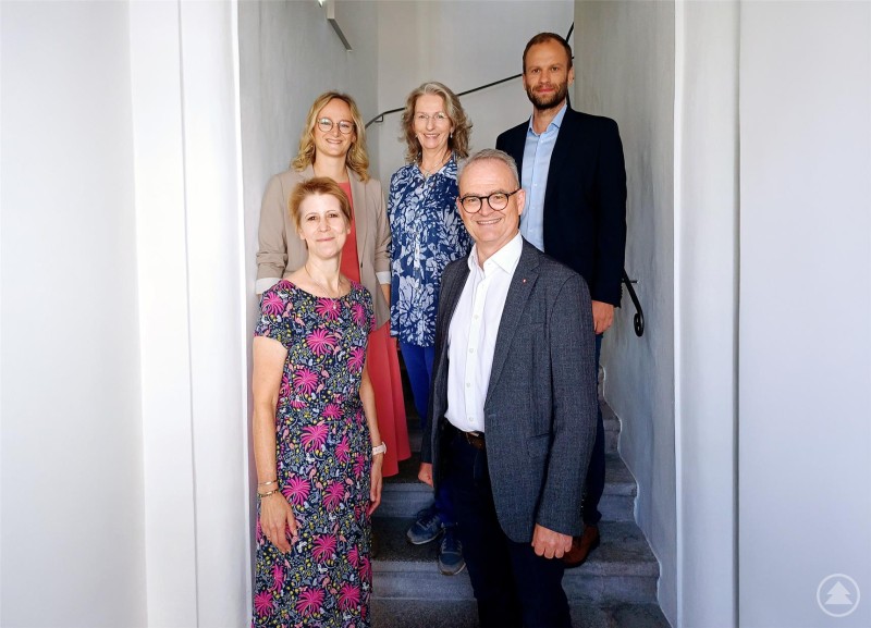 Freuen sich über den Start des neuen Programms zur Suchtprävention bei der Caritas Passau: Martina Matheisl-Schmid, Stefan Seiderer, Christina Zieglmeier, Susanne Borger und Thomas Furthmeier. Fünf Personen stehen auf einer Treppe in einem hellen Gebäude. Zwei Frauen und drei Männer blicken lächelnd in die Kamera, einige tragen Geschäfts- bzw. Bürokleidung.