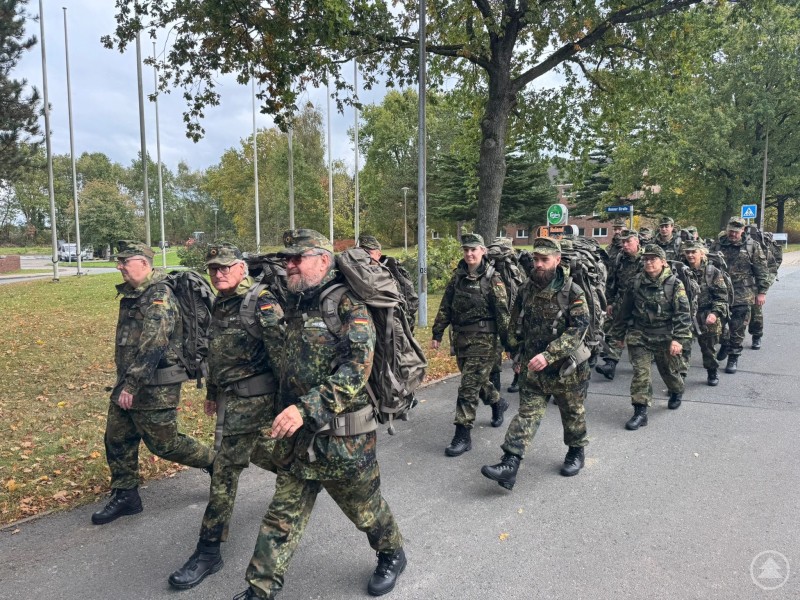 Bundeswehrangehörige beim Marsch im Rahmen der InfoDVag, ausgerüstet mit Rucksack und Gefechtsanzug.