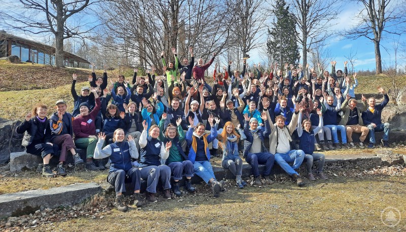Gruppenfoto aller Teilnehmenden mit dem Betreuer- und Referententeam. Die Teilnehmenden des Commerzbank-Umweltpraktikums sowie das Betreuer- und Referententeam sitzen und stehen für ein gemeinsames Gruppenfoto im Freien und heben die Arme in die Höhe.