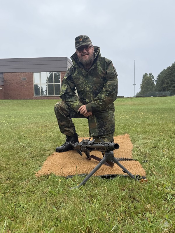 Gerhard Drexler kniet auf dem Schießplatz neben einem MG, bereit für die Einweisung ins Waffensystem.