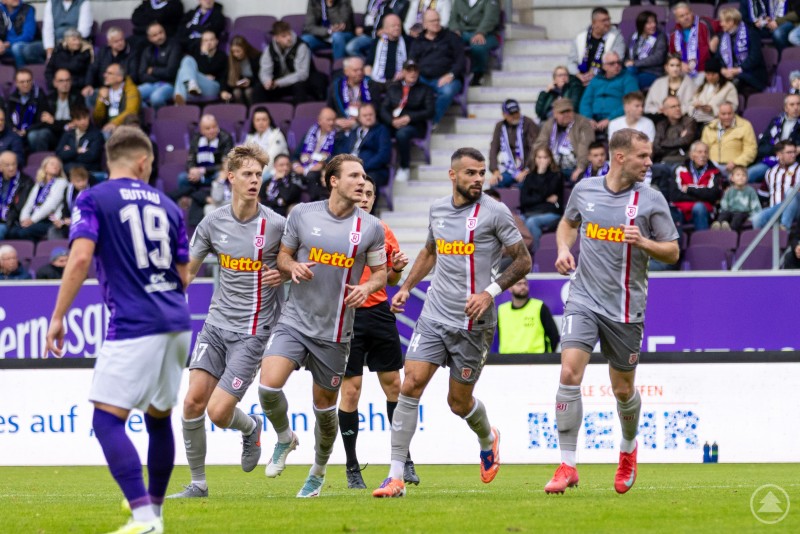 Jubel nach dem Ausgleichstreffer – die Jahnelf zeigte große Moral und kämpfte sich mehrfach zurück ins Spiel. Spieler des SSV Jahn Regensburg jubeln nach einem Tor gemeinsam auf dem Spielfeld, während Zuschauer auf der Tribüne applaudieren.