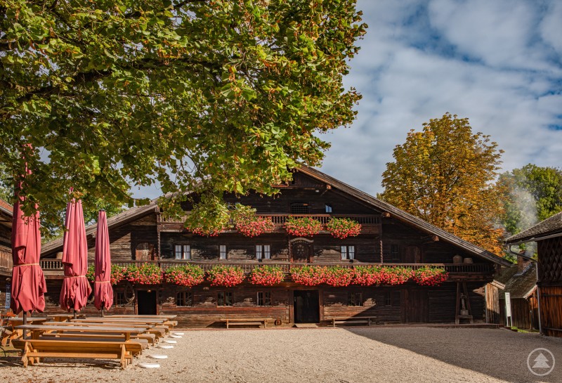 Frühling im Freilichtmuseum Massing: Nicht nur die vielen Stammgäste dieses einzigartigen Museums freuen sich schon auf den Beginn der diesjährigen Saison. Ein historisches Bauernhaus im Freilichtmuseum Massing mit blühenden Bäumen im Vordergrund und Frühlingsstimmung rund um das Gelände.