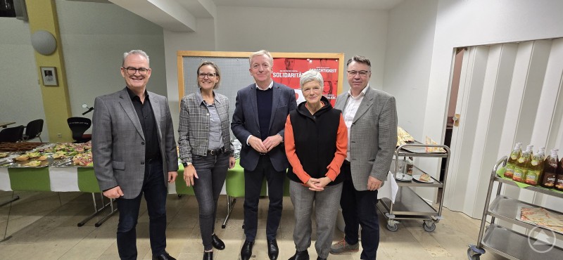 Die Caritasvorstände mit den Aufsichtsräten beim Caritasrat (v. l.): Stefan Seiderer, Andrea Anderlik, Dr. Josef Sonnleitner, Prof. Dr. Carola Jungwirth und Helmut Wurm. Fünf Personen stehen nebeneinander in einem Raum vor einem Buffet mit belegten Brötchen. Im Hintergrund sind Caritas-Plakate zu sehen.