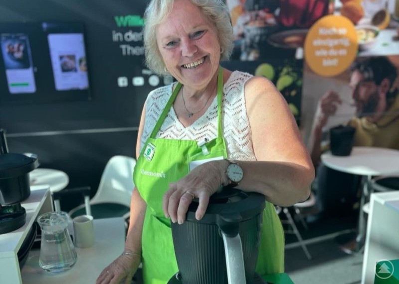 Rosi Kellermeier hat eine Berufung gefunden, die zu ihr passt. Rosi Kellermeier mit leuchtend grüner Schürze am Messestand mit ihrem Thermomix.