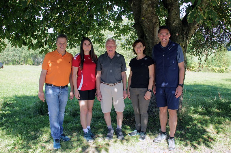 Zeigten sich erfreut über den großen Zuspruch bei der Bürgerwanderung (von links): Alexander Mayer (Bürgermeister Grafenau), Johanna Anetzberger (Tourismusreferentin Landkreis FRG), Willi Schindler, Martina Weber (Touristinfo Grafenau) und Landrat Sebastian Gruber. Fünf Personen stehen lächelnd im Schatten eines großen Baumes auf einer Wiese. Im Hintergrund sind Bäume und Wiesen in spätsommerlicher Landschaft zu sehen.