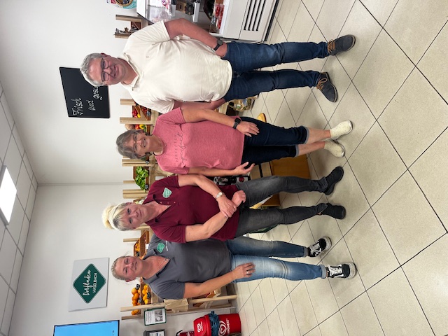 Das Team des Dorfladens Haselbach sorgt mit Herzblut für regionale Nahversorgung und persönliche Beratung. Vier Personen stehen gemeinsam im Dorfladen Haselbach und lächeln in die Kamera. Hinter ihnen sind frisches Obst und Gemüse in Holzkisten zu sehen. Die freundliche Atmosphäre spiegelt das Engagement und den Teamgeist des Ladenteams wider.