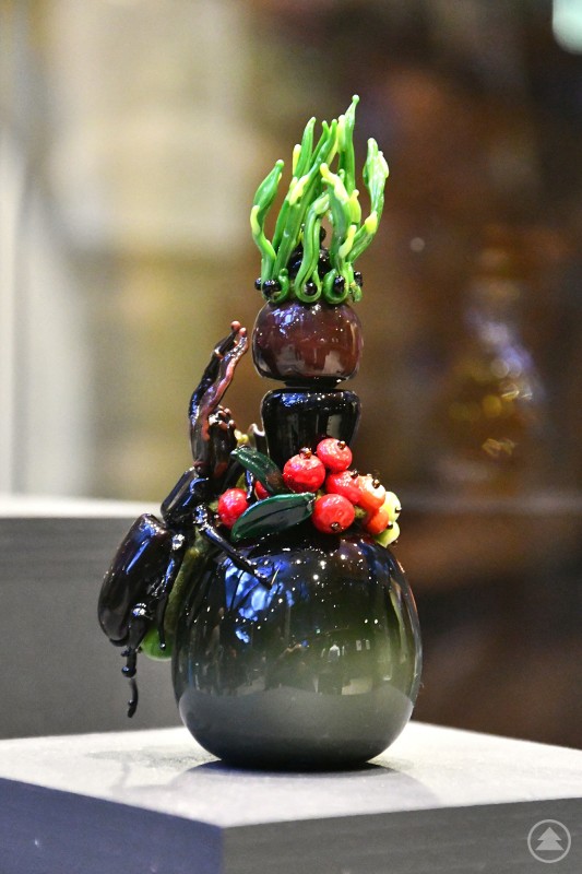 Noch bis 9. November im Haus zur Wildnis zu sehen: Die Sonderausstellung zum „Snuff Glass Award“. Im Bild ein Werk von Magdalena Paukner aus Lindberg. Eine kunstvoll gestaltete Glaskunst-Skulptur zeigt ein farbenfrohes, detailreiches Objekt mit pflanzlichen und tierischen Elementen.
