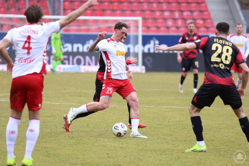 Mittelfeldspieler des SSV Jahn behauptet den Ball gegen zwei Gegenspieler im Strafraum.