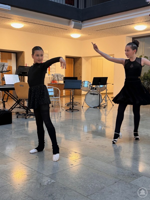 Tanzdarbietung sorgt für Abwechslung im Konzertprogramm.Lavin Ramadan 5a und Zarina Tovmazian tanzten „Born to dance“ Zwei junge Tänzerinnen führen eine Choreografie in schwarzen Outfits in einer Aula auf.
