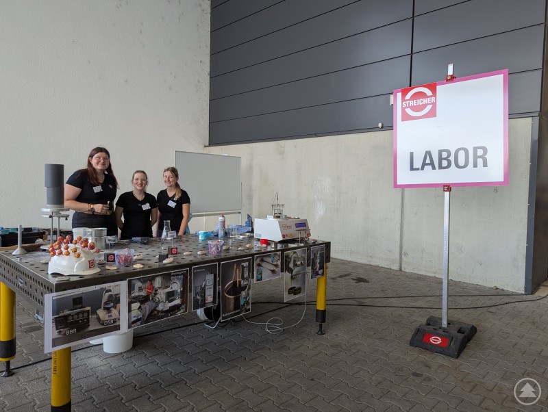 Drei Mitarbeiterinnen von MAX STREICHER hinter ihrem Mitmachstand