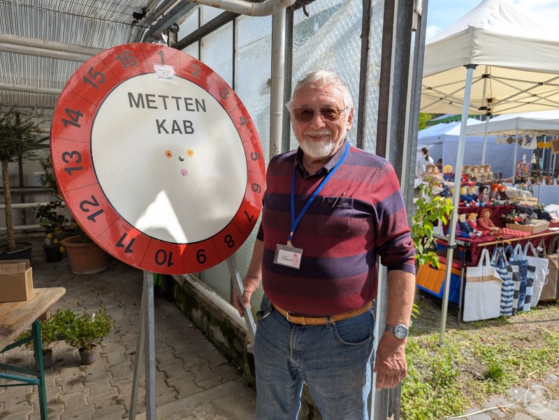 Mit ein wenig Glück konnte man am Rad drehen und florale Preise direkt aus der Klostergärtnerei gewinnen Vereinsmitglied der KAB Metten neben Glücksrad für den guten Zweck