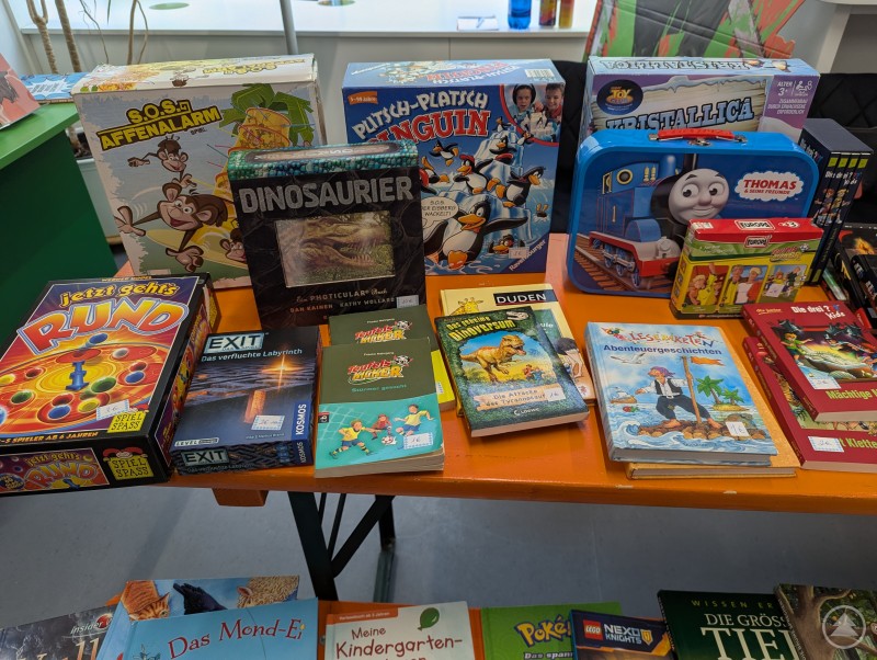 Ein Blick auf die Flohmarkttische sorgte für Begeisterung bei den kleinen und Nostalgie bei den großen Gästen. Kinderspielzeug, Bücher und Brettspiele liegen auf Flohmarktstand
