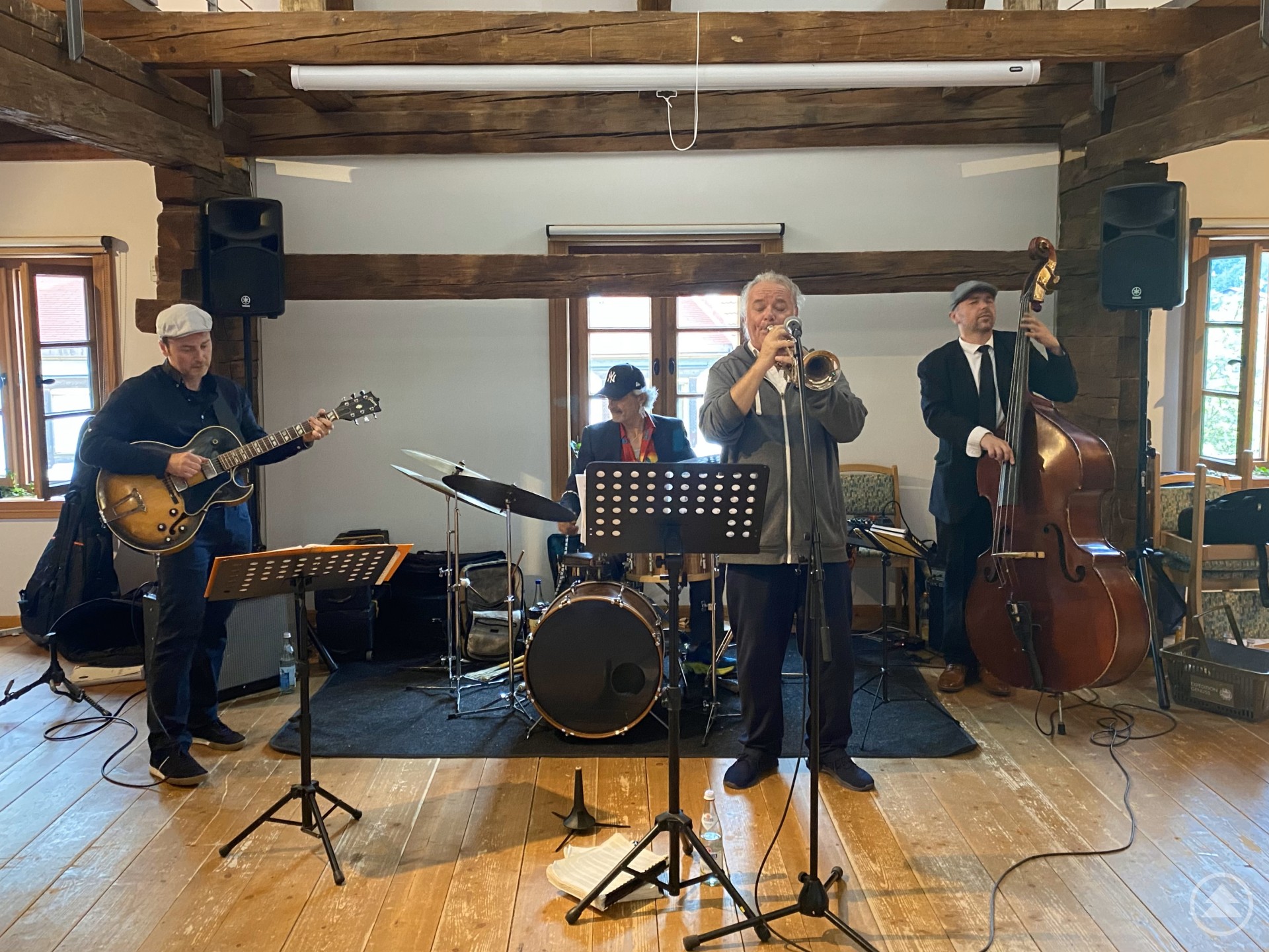 Die Jazzband „Privat Joker“ sorgte für den stimmungsvollen musikalischen Ausklang des Sommerfestes im Alten Rathaus in Bodenmais. Eine Jazzband spielt in einem historischen Raum mit Holzbalken. Vier Musiker sind zu sehen: ein Gitarrist, ein Schlagzeuger, ein Trompeter und ein Kontrabassist.