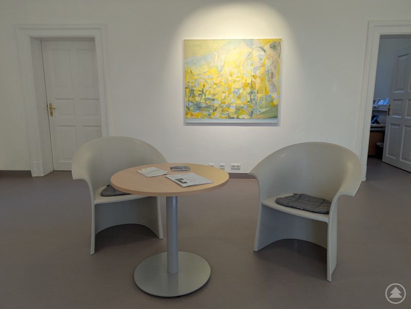 Ankommen, sich wohlfühlen und vielleicht sogar ein Kunstwerk für zu Hause ausleihen - das können alle im Haus D2. Zwei Sessel und ein Tisch mit gelbem Gemälde im Hintergrund