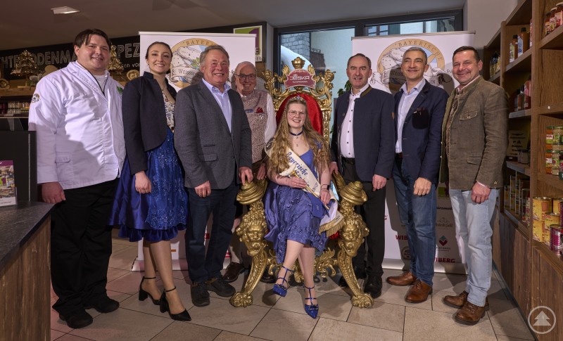 Gruppenfoto bei der Kr&ouml;nung der 11. Bayerischen Wei&szlig;wurstk&ouml;nigin in Bodenmais. Die neue K&ouml;nigin sitzt auf einem goldenen Thron, umgeben von Vertretern aus Politik und Handwerk.
