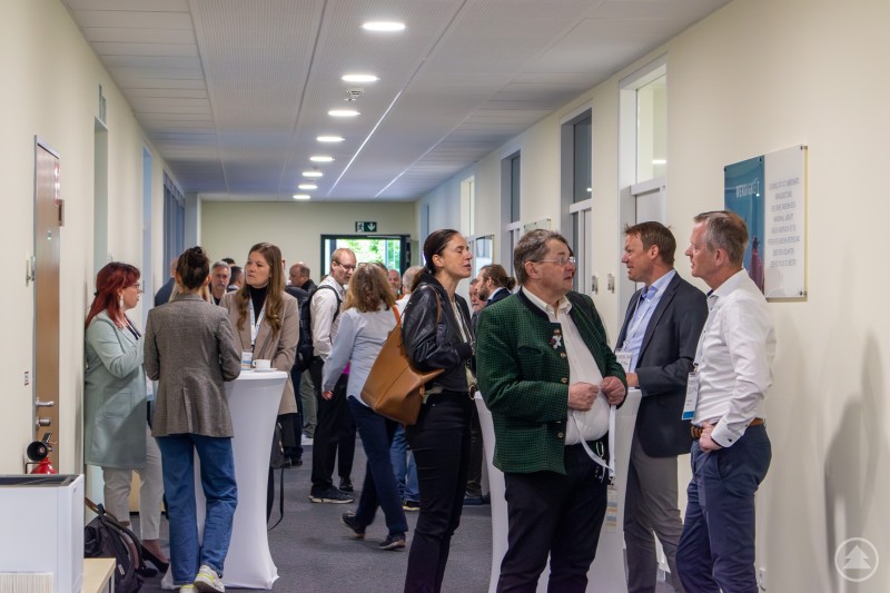 Der Digital Tag bietet zahlreiche Gelegenheiten zum Networking und Austausch zwischen Forschung und Wirtschaft. Besucherinnen und Besucher des Digital Tags tauschen sich während einer Pause im Flur aus, teils an Stehtischen stehend.