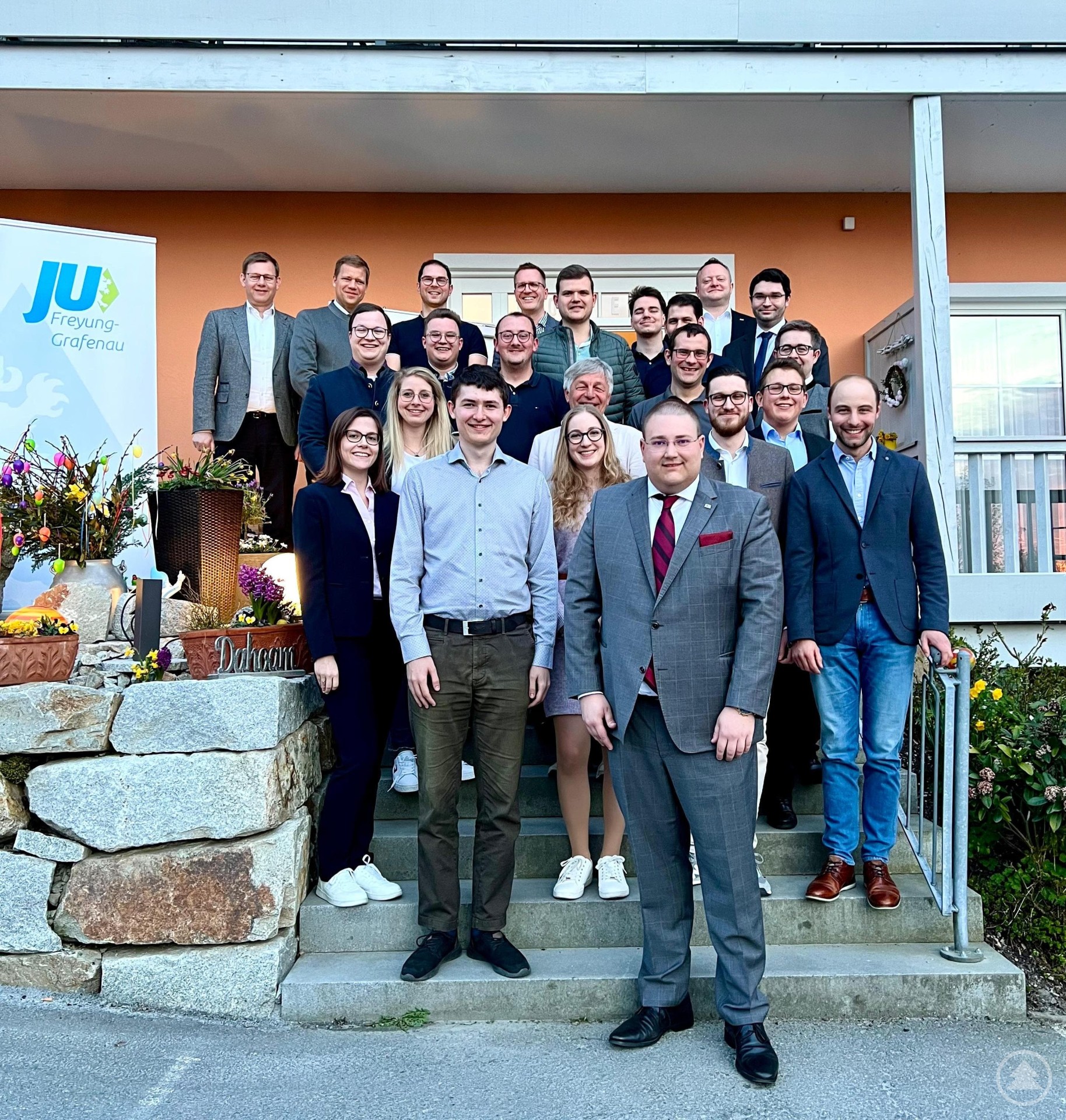 Gewählte und Ehrengäste bei der Kreismitgliederversammlung der Jungen Union Freyung-Grafenau: (hintere Reihe, v. li. n. re.) MdB Thomas Erndl, Bezirkstagspräsident und CSU-Kreisvorsitzender Dr. Olaf Heinrich, Bernhard Bachhuber, stellv. CSU-Ortsvorsitzender Alexander Seidl, Martin Höppler, Xaver Wilhelm, Sebastian Schrank, MU-Kreisvorsitzender Stefan Behringer, stellv. JU-Bezirksvorsitzender Marcus Wagner, (mittlere Reihe, v. li. n. re.) JU-Bezirksgeschäftsführer Julien Pursch, JU-Kreisvorsitzender von Regen Michael Süß, Ludwig König, Bürgermeister Leo Meier, Daniel Wagner, JU-Kreisvorsitzender von Deggendorf Stefan Zitzelsberger, (vordere Reihe, v. li. n. re.) Laura Dick, Sabrina Lucksch, Michael Scherzer, Anna Trauner, JU-Kreisvorsitzender Christoph Weishäupl, Fabian Clasen, Jonas Höcker und Dr.-Ing. Sebastian Weber. Eine Gruppe von Mitgliedern und Ehrengästen der Jungen Union Freyung-Grafenau steht auf einer Treppe vor einem Gebäude. Im Hintergrund ist ein Banner der Jungen Union zu sehen. Die Teilnehmer sind in mehreren Reihen aufgestellt und lächeln in die Kamera.