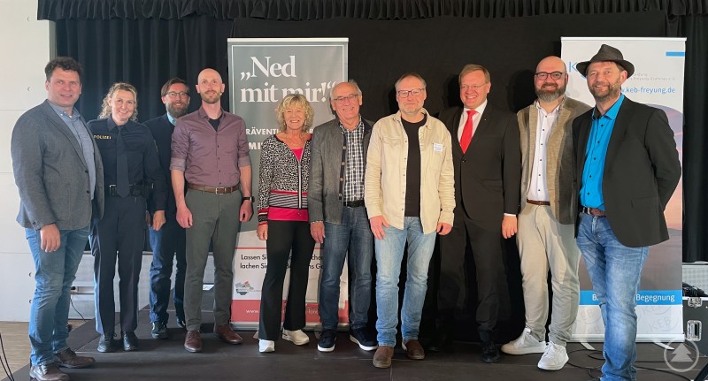 Sie möchten sicherstellen, dass Trickbetrüger keine Gelegenheit haben, Sie zu täuschen. (v.l.) Robert Stadler (KP Passau), Bettina Einberger (PI Grafenau), Christian Fiebig (Landratsamt), Präventionsbeamter Rudi Schmuderer, stellvertretende Landrätin Hilde Greiner, Günter Klampfl (2. Bürgermeister Schönberg), Michael Winichner (KEB), Dr. Mikko Klein (Sparkasse), Markus Roth (Sparkasse) und Kabarettist Tom Bauer. MM 2025-03-13 Präventionskabarett Ned mit mir begeistert das Publikum in Schönberg.JPG