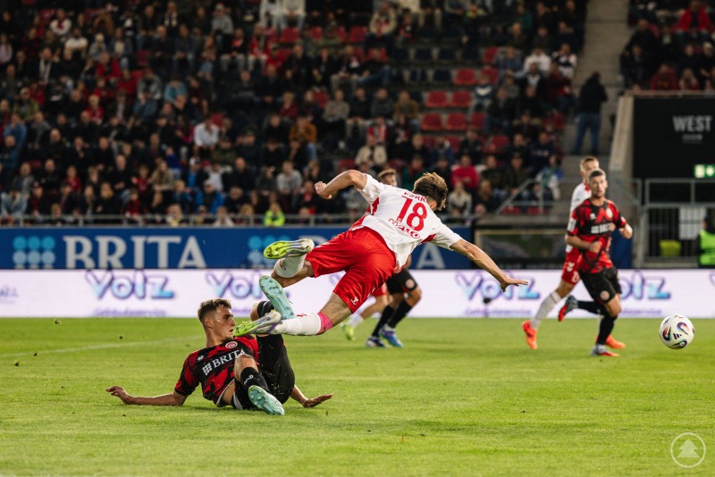 Intensiver Zweikampf: Die Partie war hart umkämpft, doch am Ende setzte sich Wiesbaden durch. Ein Regensburger Spieler fliegt nach einem harten Zweikampf durch die Luft, während ein Wiesbadener Gegenspieler am Boden grätscht.