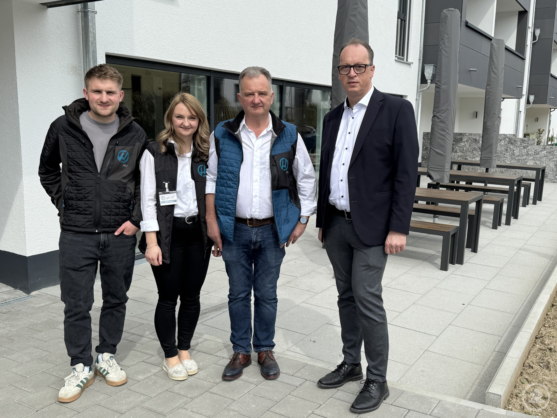 Landtagsabgeordneter Martin Behringer steht mit dem Team von Hecht Wohnbau vor einem modernen Gebäude in Grafling.