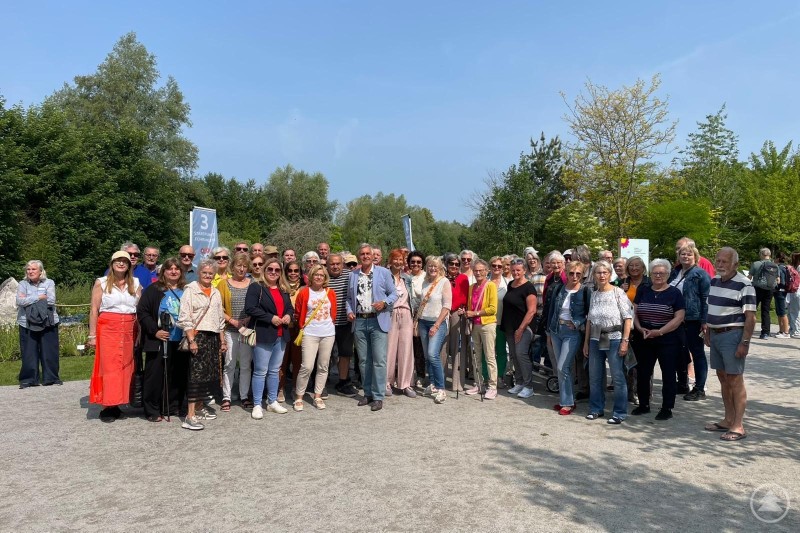 Über 300 Bürgerinnen und Bürger aus Schärding nahmen am traditionellen Ausflug zur Oö. Landesgartenschau teil. Eine große Gruppe älterer Menschen steht gemeinsam lachend im Freien vor einer grünen Parklandschaft und blickt in die Kamera.