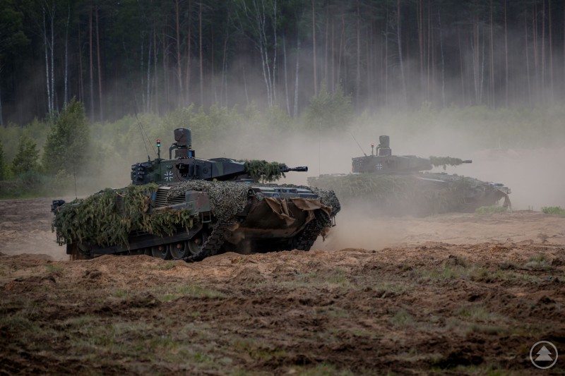 Schützenpanzer Puma mit Tarnung aus Laub im Gelände bei einer Übung, seitlich fotografiert.