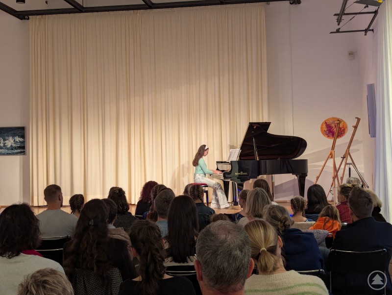 Im Obergeschoss des Kapuzinerstadls wurde die Kunstausstellung feierlich mit herzlichen Worten, Klaviermusik und beeindruckenden Turneinlagen eröffnet. Klavierschülerin spielt am schwarzen Flügel
