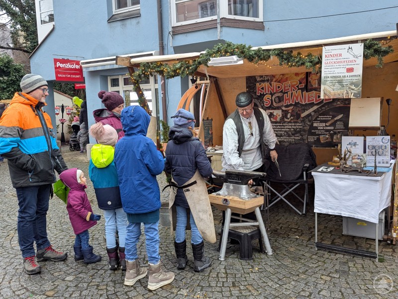Kinder stehen vor Schmiede-Stand in der Deggendorfer Kinderweihnacht