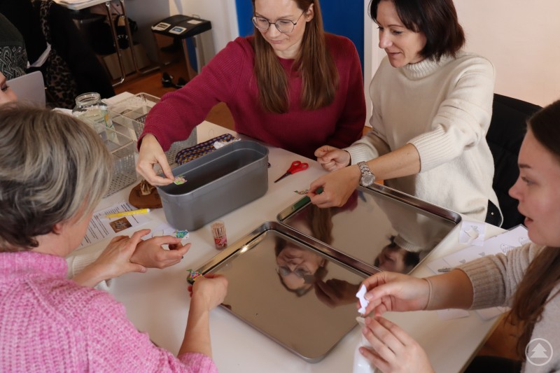 In die Rolle der Schülerinnen und Schüler schlüpften die Lehrerinnen und Lehrer aus Röhrnbach beim Workshop zum Thema Gewässer und Teichbewohner im Museum Schloss Wolfstein. Mehrere Lehrerinnen arbeiten gemeinsam an einem Tisch in einem hellen Raum. Sie sortieren und gestalten kleine Materialien und Karten, die auf Metalltabletts und in Boxen liegen. Die Atmosphäre wirkt konzentriert und kreativ.