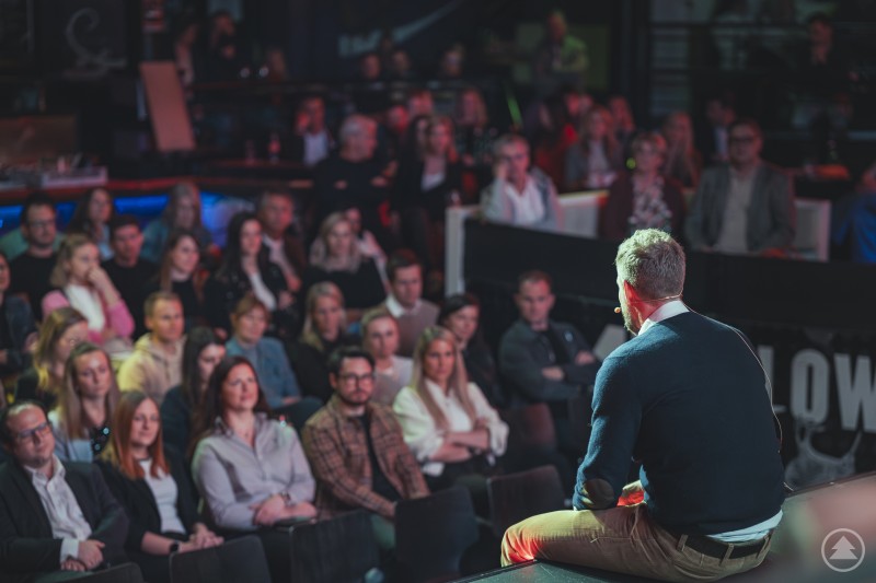 Bodo Janssen begeisterte beim IMPOSIUM 2026 mit seinen inspirierenden Vorträgen zur modernen Führungskultur. Ein Referent sitzt auf der Bühnenkante und spricht vor einem aufmerksam zuhörenden Publikum in einer modernen Eventlocation.