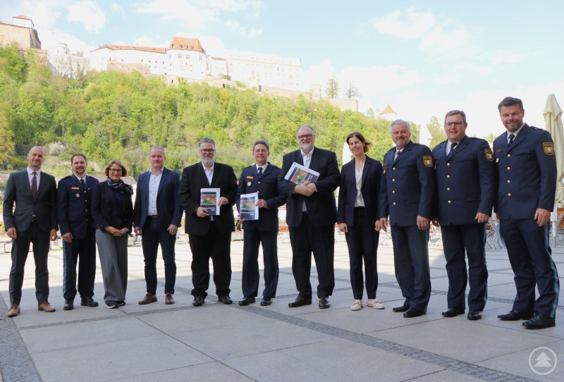 Vertreter von Polizei und Stadt Passau bei der Vorstellung des Sicherheitsberichts 2025. Gruppenfoto mehrerer Vertreter von Polizei und Stadt Passau vor einer historischen Kulisse mit Blick auf die Altstadt und ein Gebäude im Hintergrund.