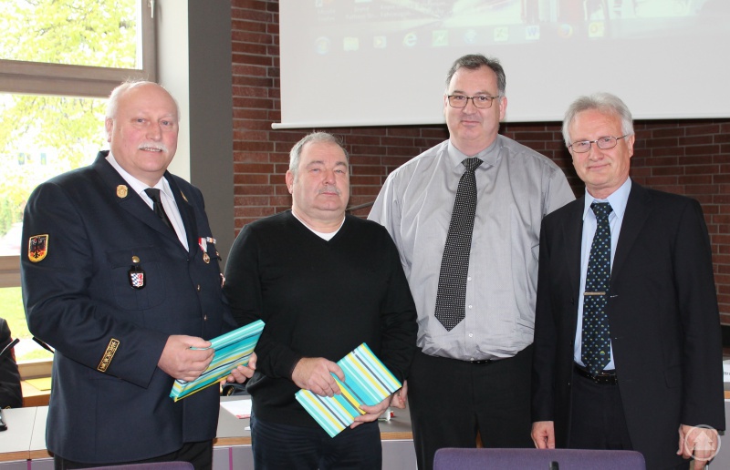 Kreisbrandrat a.D. Johann Prex und Stadtbrandrat a.D. Rainer Heimann werden von Brandamtsrat Stefan Haslbeck und Abteilungsdirektor Nikolaus Heckl mit einem Geschenk verabschiedet (von links).
