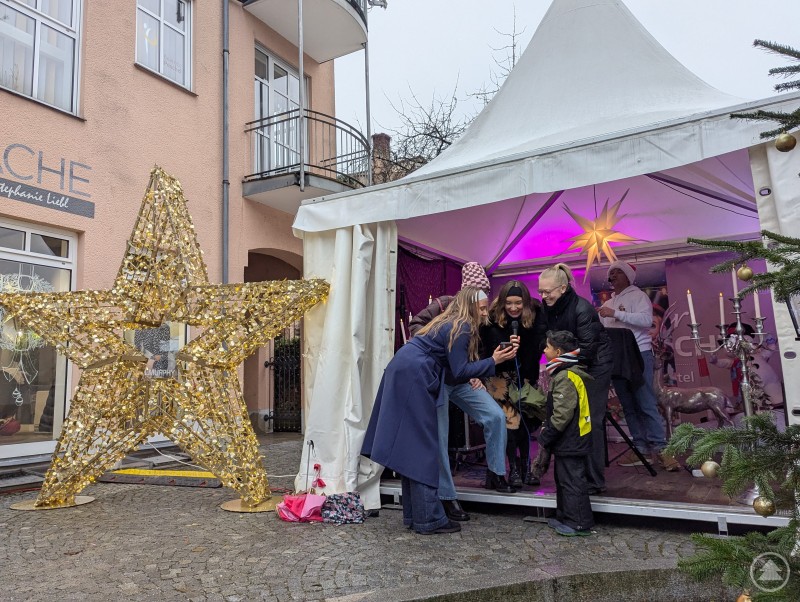 Frauen und Kinder singen Weihnachtslieder auf der sch&ouml;n dekorierten B&uuml;hne