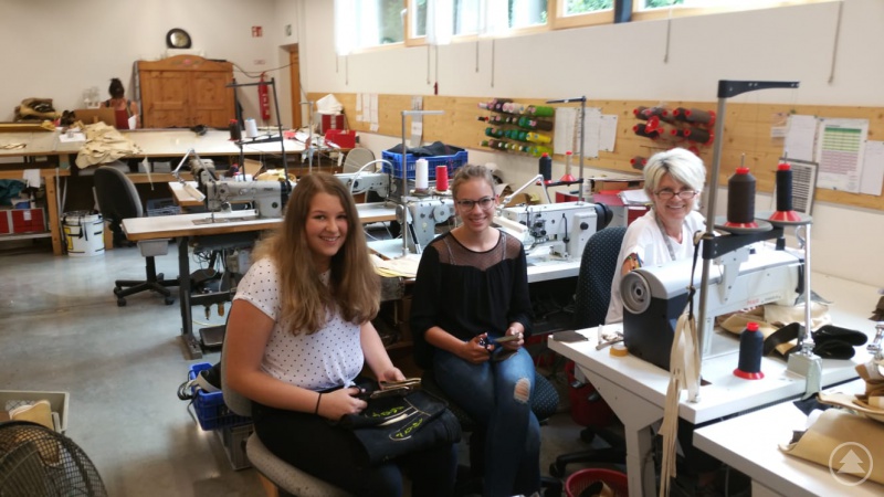 Die Schülerinnen Selina Pauli (von links) und Sophia Perl mit einer Mitarbeiterin von Trachten Freund bei der Fertigung von Lederhosen.