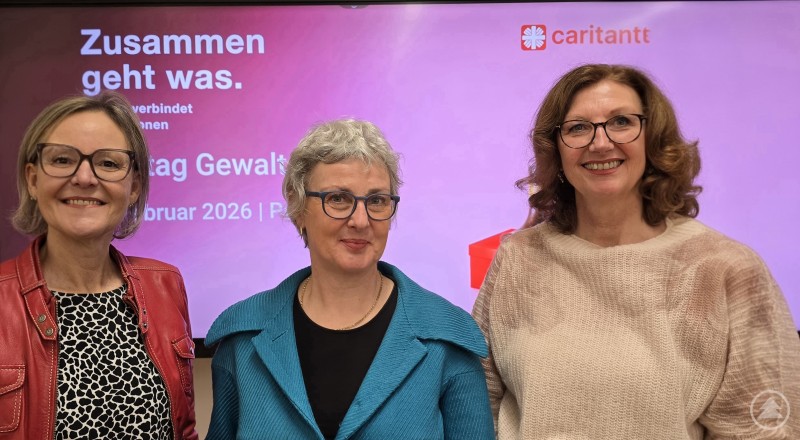 Gemeinsam für Gewaltschutz in der Pflege: Caritasdirektorin Andrea Anderlik, Prof. Dr. Ursula Immenschuh und Andrea Kramer, Präventionsbeauftragte der Caritas, beim Fachtag zur Prävention in Passau. Drei Frauen stehen nebeneinander vor einer Präsentationswand mit dem Schriftzug „Zusammen geht was“. Alle drei lächeln in die Kamera. Sie tragen Brillen und sind gepflegt gekleidet. Im Hintergrund ist das Logo der Caritas sowie der Titel einer Fachveranstaltung zur Prävention im Pflegebereich zu sehen.