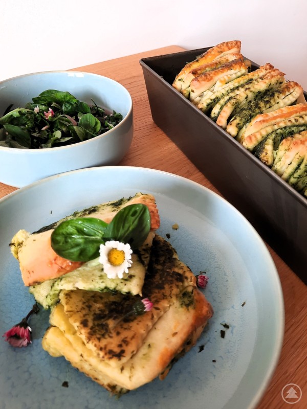 Frisch gebackenes Bärlauch Zupfbrot mit Wildkräutersalat Nahaufnahme von angerichtetem Bärlauch Zupfbrot mit Salat auf einem Tisch