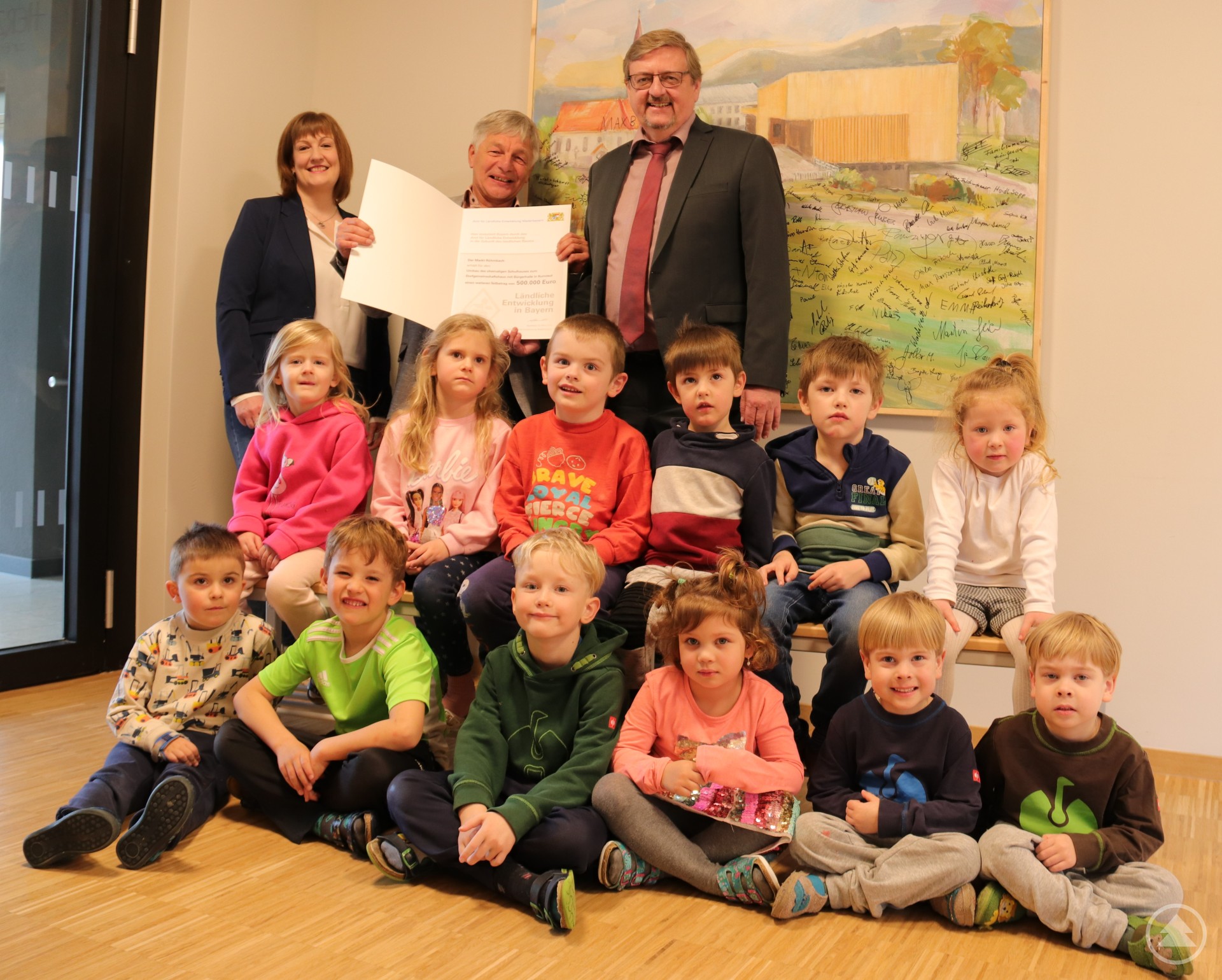 Im Beisein von Kindergartenkindern überreichte ALE-Leiter Hans-Peter Schmucker (r.) an Röhrnbachs ersten Bürgermeister Leo Meier (Mitte) und Kämmerin Stefanie Graf-Riedl ein weiteres Förderpaket über 500.000 Euro für das Dorfgemeinschaftshaus mit Bürgerhalle.