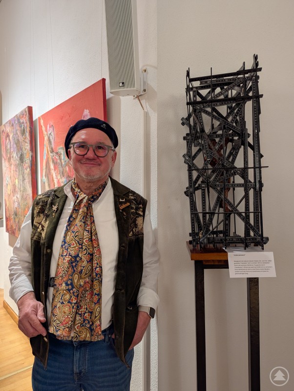 Diether Speth steht vor seiner Skulptur aus Holz 