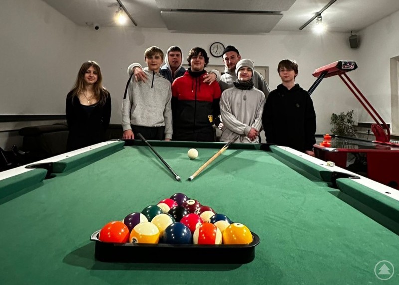 Die Gewinner des Turnieres Gruppe von Jugendlichen steht hinter einem Billardtisch, vorne liegen die aufgebauten Billardkugeln, aufgenommen in einem hellen Innenraum.