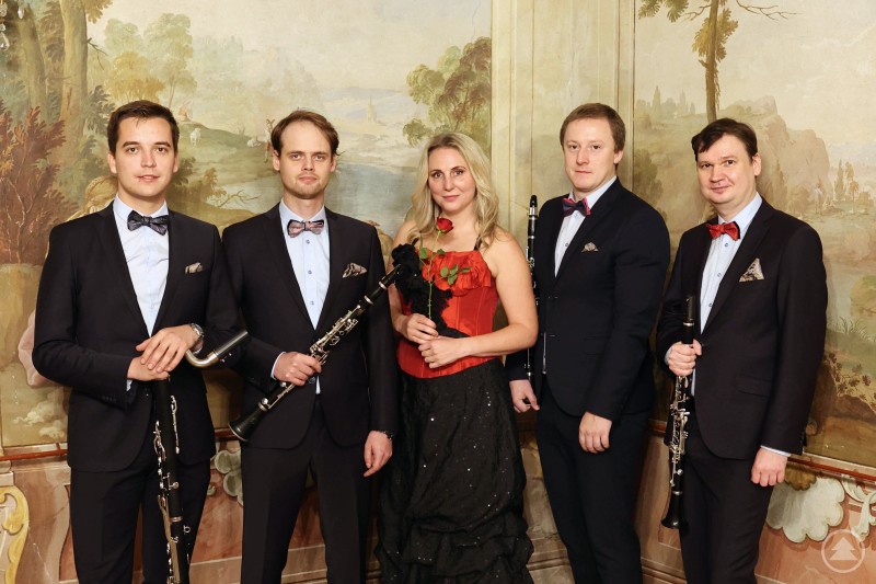 Das Klarinettenensemble Prachatice begeistert am 22. Juni 2025 mit einem Konzert im Fürstenzimmer von Schloss Wolfstein. Fünf Musiker:innen in eleganter Kleidung, drei Männer mit Klarinetten, eine Frau in rotem Corsagen-Oberteil hält eine Rose, vor einem malerischen Hintergrund in einem historischen Raum.