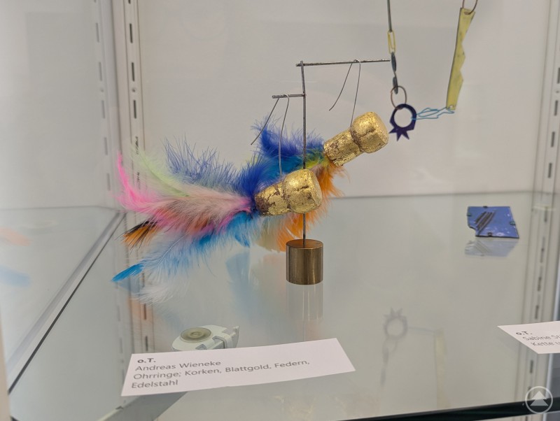 Andreas Wieneke lässt in seinem Werk ohne Titel die Korken knallen und Augen strahlen. Ohrringe aus Weinflaschen-Korken und bunten Federn